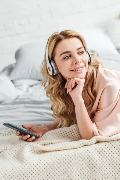 Boldog Lány Fülhallgató Hallgatás Zene Gazdaság Okostelefon Hálószobában — Stock Fotó