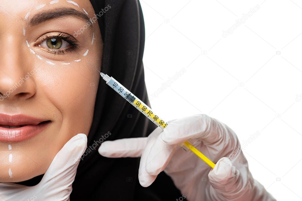 cropped view of young Muslim woman in hijab with marks on face having beauty injection isolated on white