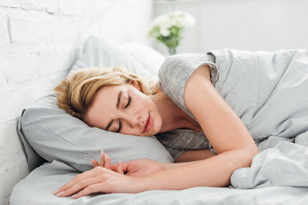 attractive woman sleeping under blanket at home 