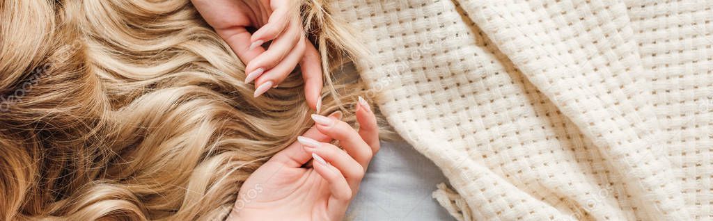 panoramic shot of young blonde woman lying on bed 