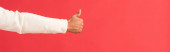 panoramic shot of man showing thumb up isolated on red 