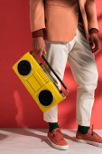oříznutý pohled na stylového muže držícího boombox na červené se stíny 
