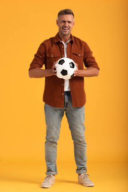 Duygusal adam futbol oynuyor ve turuncu üzerinde duruyor. 
