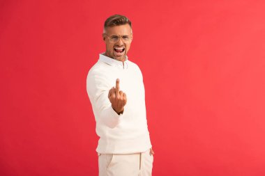 Kırmızıda izole edilmiş orta parmağını gösteren gözlüklü kızgın adam. 