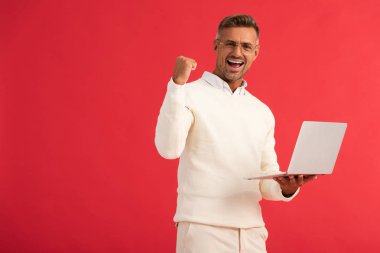 Kırmızı ekranda dizüstü bilgisayarı tutan heyecanlı adam. 