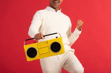 Kırmızıda izole edilmiş retro teyp tutan mutlu adamın görüntüsü. 