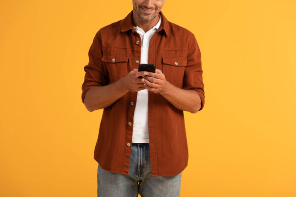 обрезанный вид счастливого человека с помощью смартфона изолированы на оранжевый
 