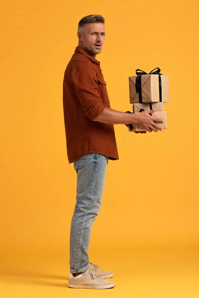 Έκπληκτος Άνθρωπος Κρατώντας Δώρα Ενώ Στέκεται Πορτοκαλί — Φωτογραφία Αρχείου