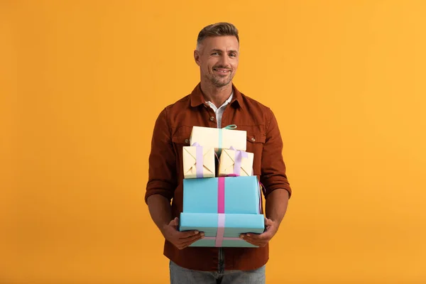 Hombre Guapo Sonriendo Mientras Sostiene Cajas Regalo Aisladas Naranja —  Fotos de Stock