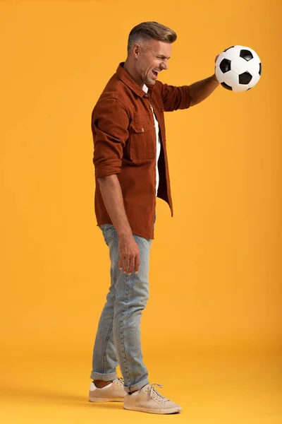 オレンジの上に立ちサッカーを続ける怒れる男 — ストック写真