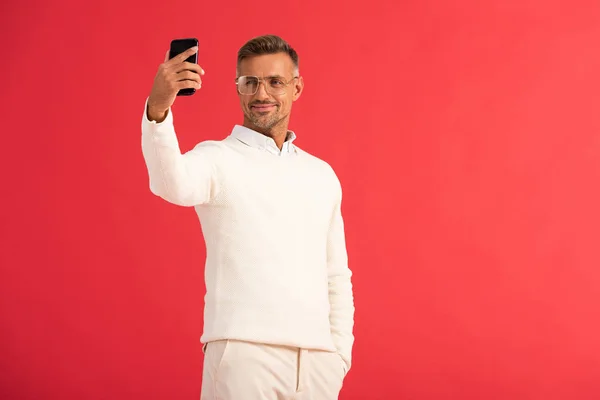 Homem Feliz Óculos Tomando Selfie Enquanto Segurando Smartphone Isolado Vermelho — Fotografia de Stock