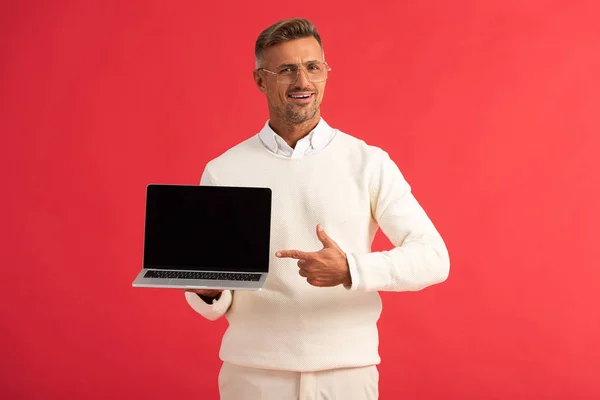 Szczęśliwy Człowiek Okularach Wskazując Palcem Laptopa Pustym Ekranem Odizolowany Czerwono — Zdjęcie stockowe