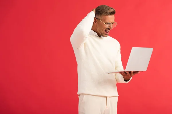 Ontevreden Man Bril Houden Laptop Geïsoleerd Rood — Stockfoto