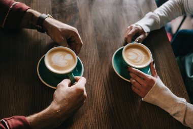 Kahve dükkanının balkonunda cappuccino içen çift manzarası.