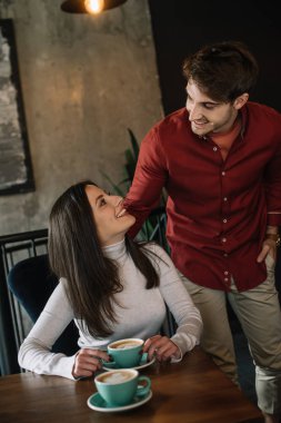 Gülümseyen genç çift kahve dükkanının balkonunda birbirlerine bakıyorlar.