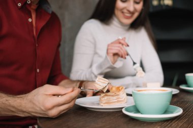 Mutlu çiftin peynirli kek yediği ve kahve dükkanında cappuccino içtiği görüntüler.