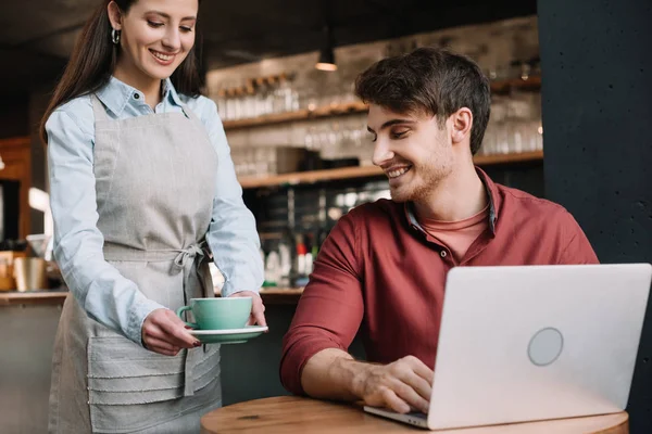 Leende Servitris Serverar Kaffe Till Frilansare Med Laptop — Stockfoto