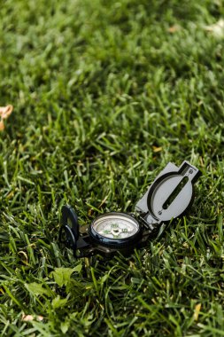 selective focus of black and vintage compass on green grass  clipart