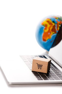 Dünya yakınlarındaki dizüstü bilgisayardaki oyuncak kutusunun seçici odak noktası beyaz, e-ticaret konseptinde izole edilmiş.