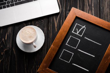 Tebeşir panosunun en üst görüntüsü, kahve ve dizüstü bilgisayarın yanında kontrol listesi, masa, e-ticaret konsepti