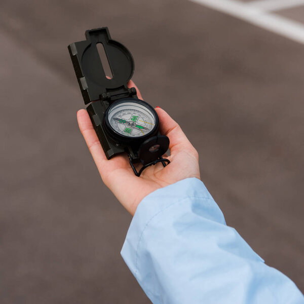 close up of woman holding compass near road 