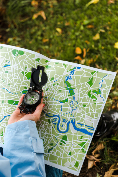 cropped view of woman holding map and vintage compass outside 