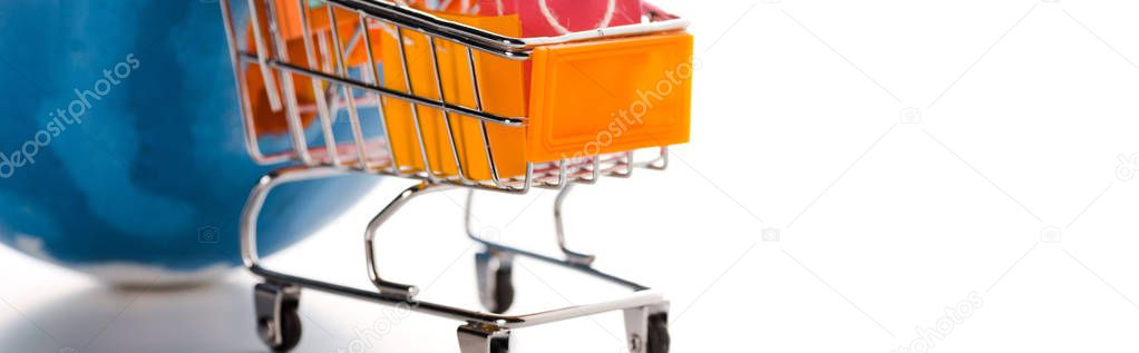 panoramic shot of toy shopping cart with shopping bags near globe on white, e-commerce concept