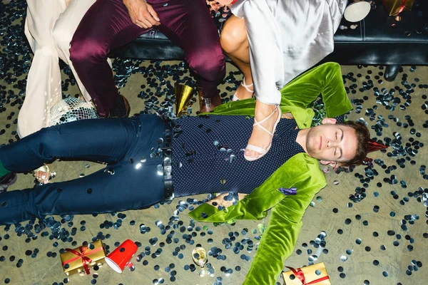 Przystojny Pijany Człowiek Śpi Podłodze Pobliżu Przyjaciół Confetti Imprezie — Zdjęcie stockowe