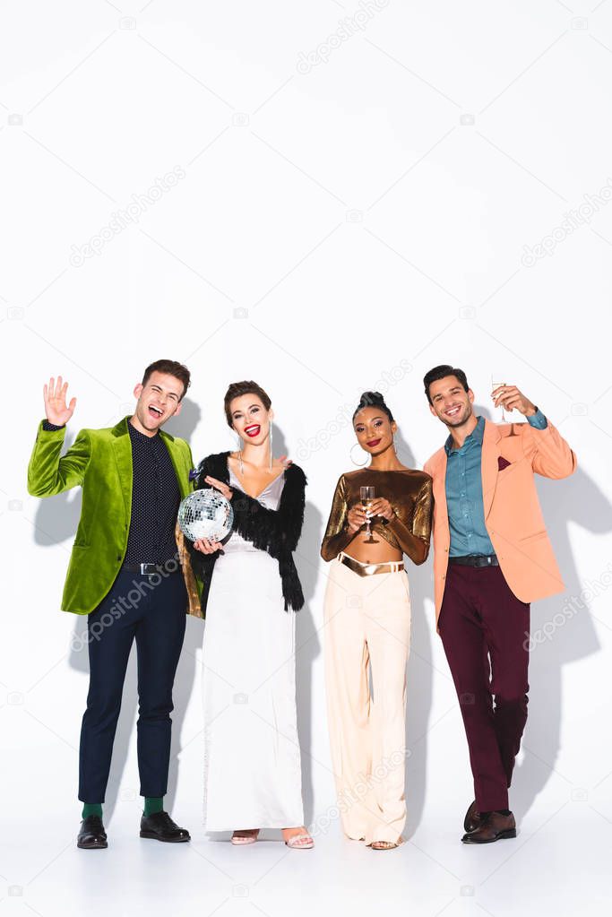 happy multicultural friends holding champagne glasses and disco ball on white 