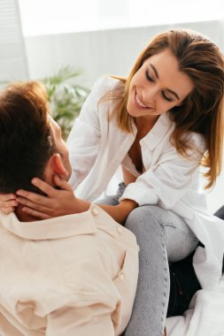 Gülümseyen ve çekici kız arkadaş evde oturuyor ve erkek arkadaşına sarılıyor. 