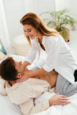 Gülümseyen ve çekici kız arkadaş evde oturuyor ve erkek arkadaşına sarılıyor. 