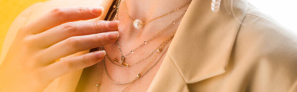 panoramic shot of woman touching necklace on white and yellow 