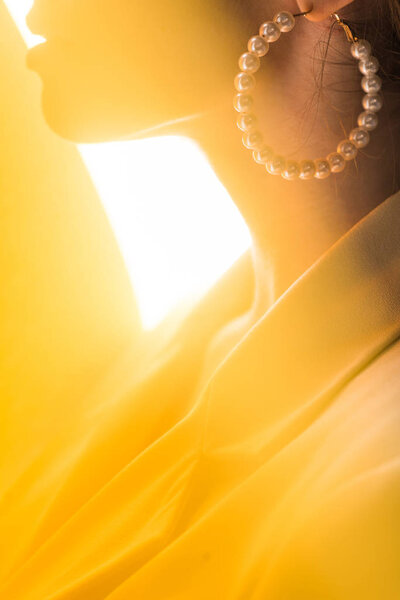 cropped view of stylish woman with pearl earring on white and yellow 