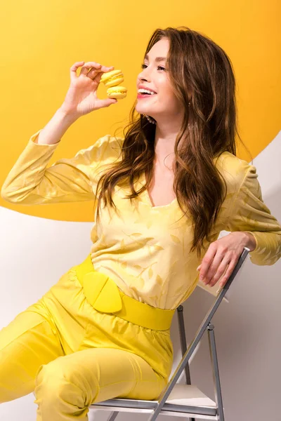 Mulher Feliz Segurando Macarons Enquanto Sentado Laranja Branco — Fotografia de Stock