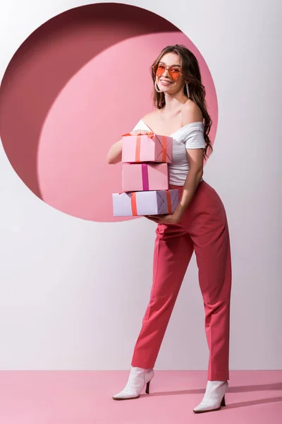 Ευτυχισμένη Γυναίκα Κρατώντας Δώρα Ενώ Στέκεται Ροζ Και Άσπρο — Φωτογραφία Αρχείου