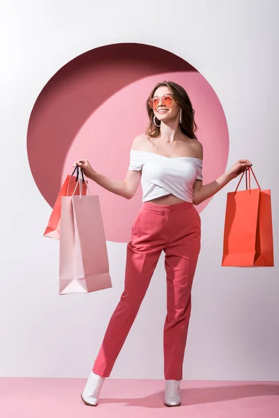 Mulher Alegre Óculos Sol Segurando Sacos Compras Rosa Branco — Fotografia de Stock