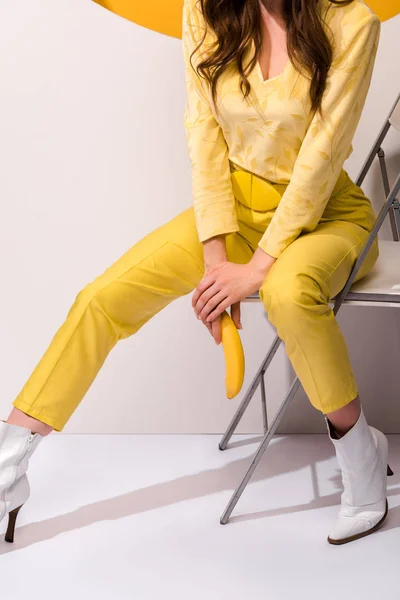 Cropped View Woman Sitting Chair Holding Banana White Orange — Stock Photo, Image