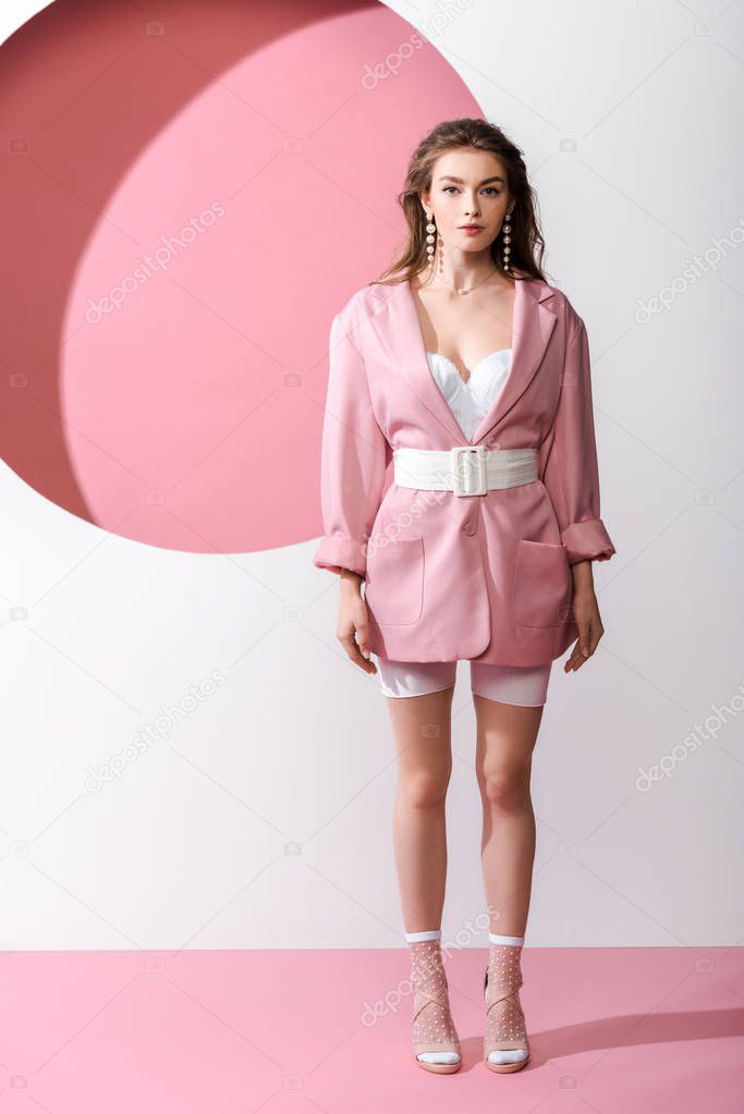 stylish girl standing and looking at camera on white and pink 