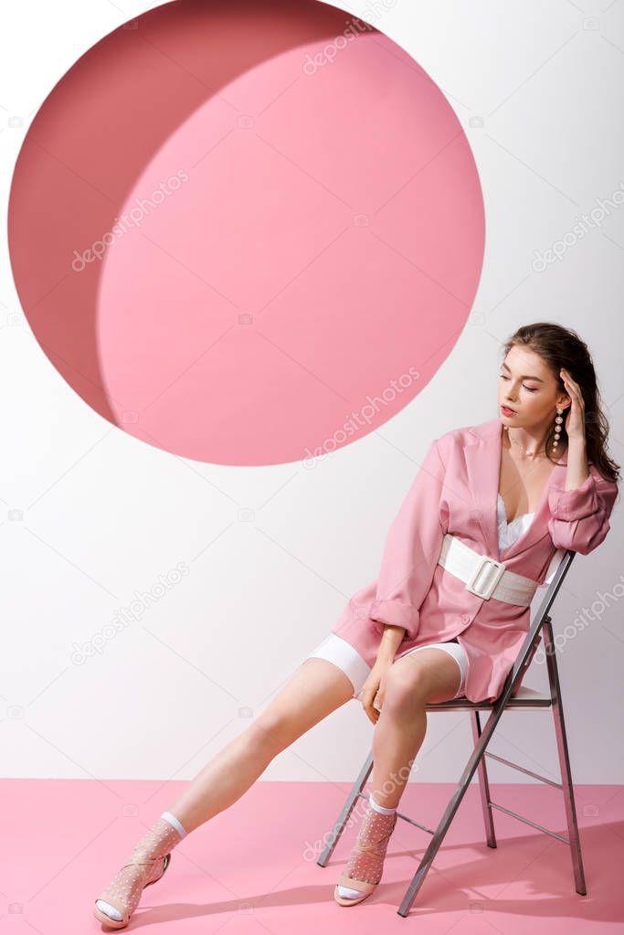 pensive girl sitting on chair on white and pink 