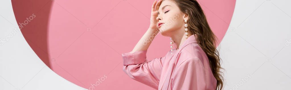 panoramic shot of beautiful girl touching hair on white and pink 