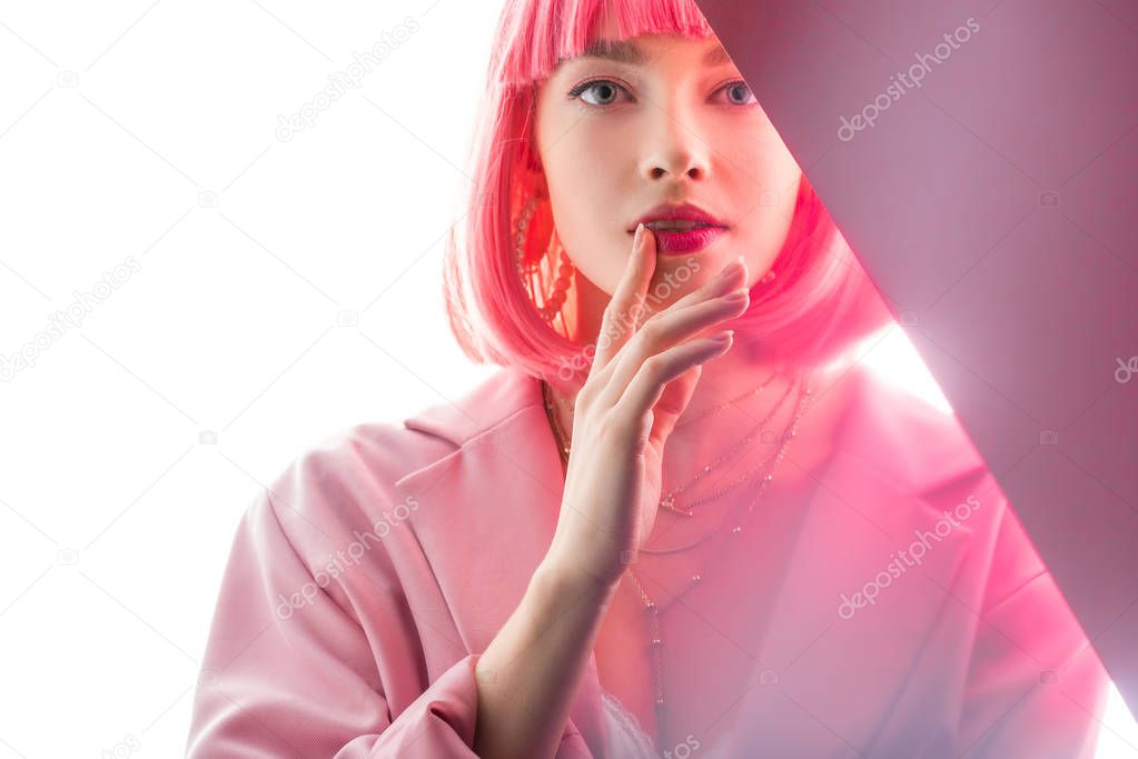 attractive woman touching lips and looking at camera on white and pink 