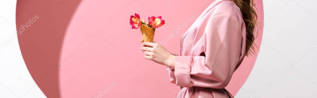 panoramic shot of woman holding ice cream cone with flowers on white and pink 