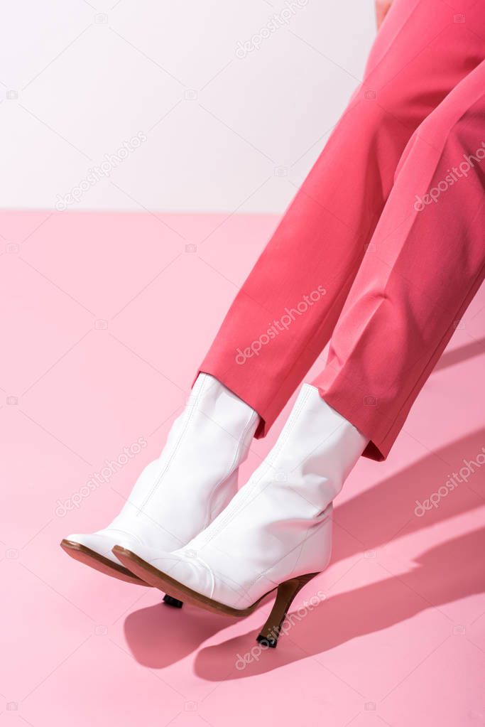cropped view of girl in boots on white and pink 