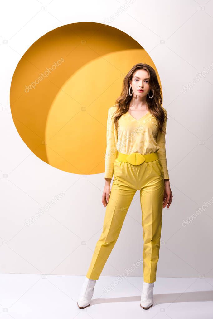 stylish girl looking at camera while standing on orange and white 