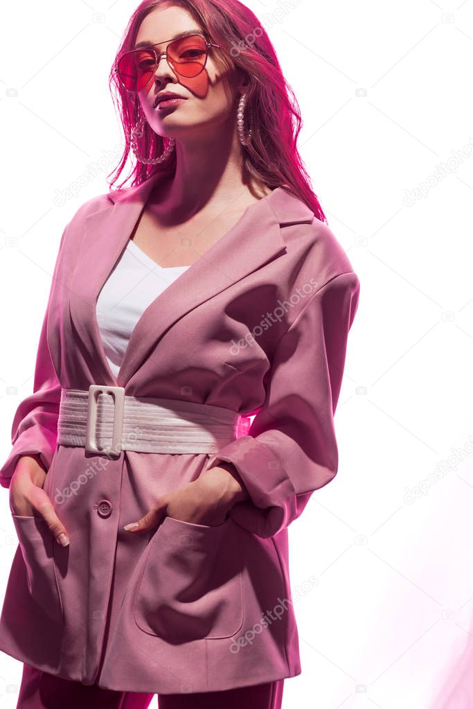 attractive woman standing with hands in pockets on white 