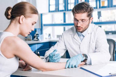 Klinikte kadının yanında şırınga tutan alerji uzmanının seçici odağı 