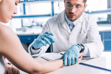 Plastik eldivenli alerji uzmanının seçici odağı klinikte çekici bir kadının yanında şırınga tutuyor. 