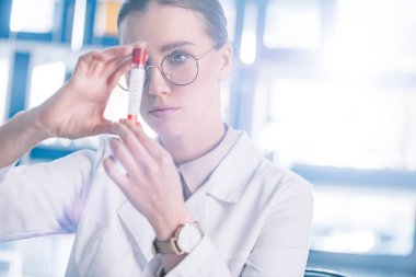 selective focus of beautiful immunologist in glasses holding test tube  clipart