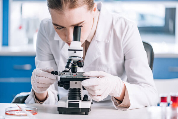 attractive immunologist looking through microscope in laboratory 