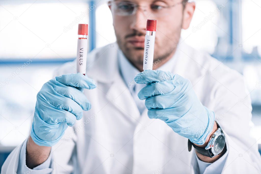 selective focus of bearded immunologist holding test tubes with letters 